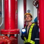 Engineers inspecting the inside plumbing and water valves of an industrial facility.