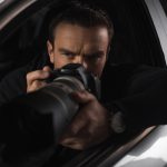 concentrated paparazzi spying by camera with object glass from his car