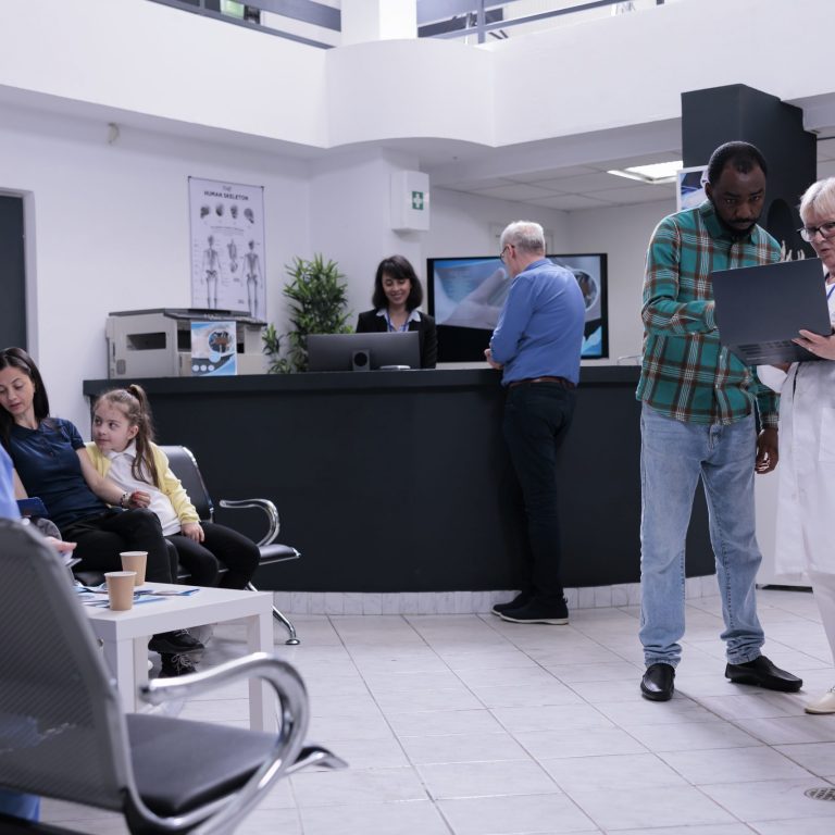 Senior medical doctor holding laptop presenting lab results to african american patient in private practice clinic. Older medic talking with man checking appointment on portable computer.